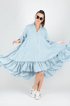 Woman wearing a light blue linen dress with ruffles on a white background