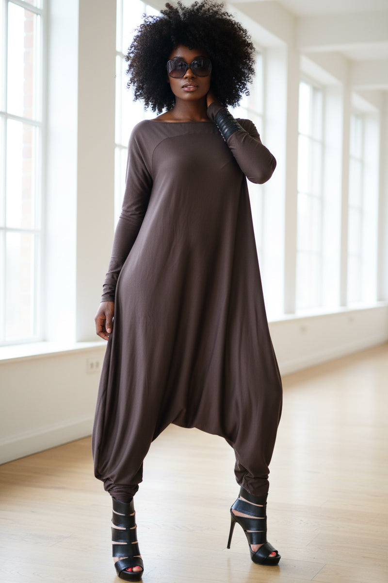 Woman wearing a brown long-sleeve dress in a bright room with large windows.
