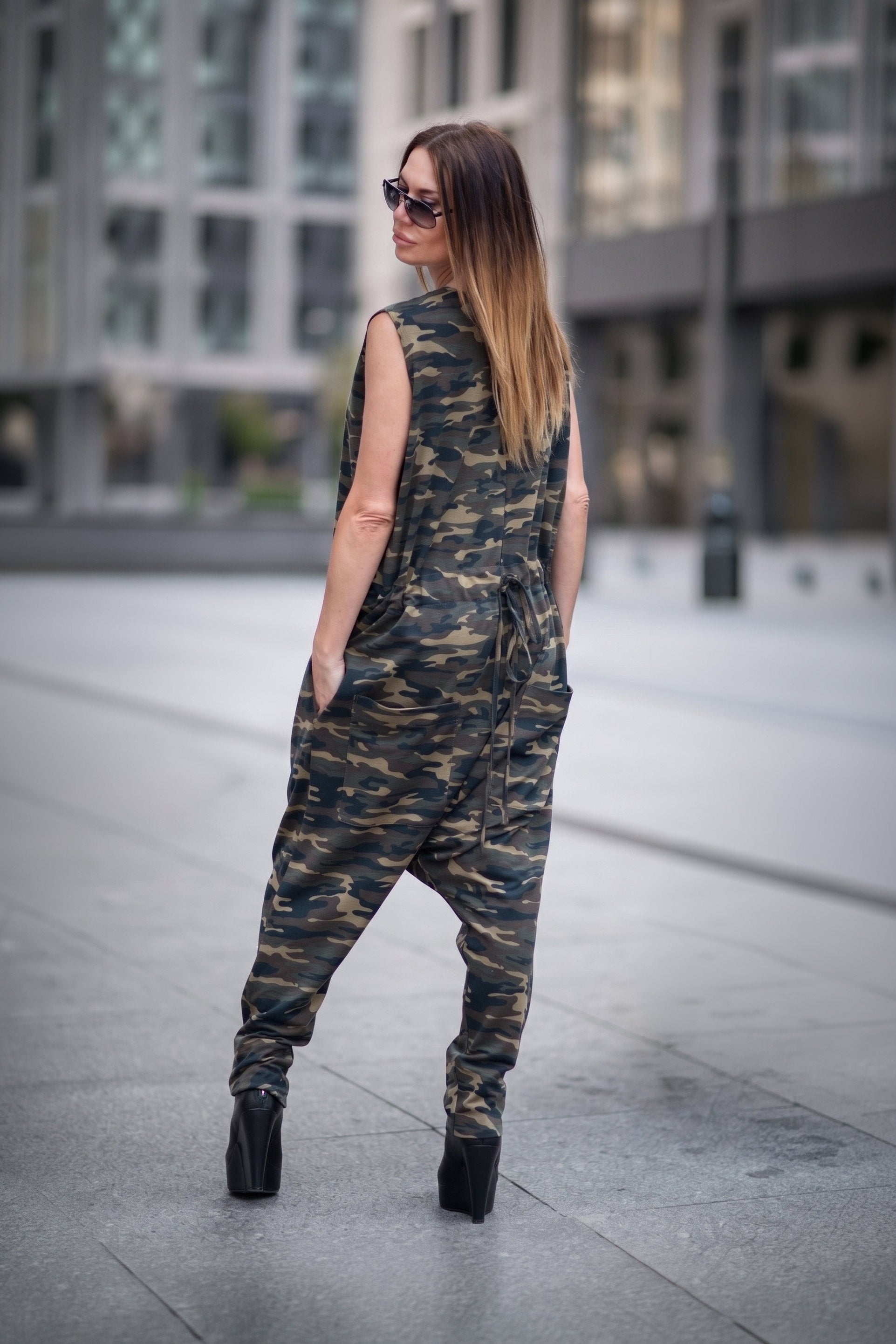 Woman wearing a camouflage jumpsuit walking on a city street.