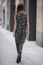 Woman wearing a camouflage jumpsuit walking on a city street.