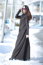 Woman wearing a long black dress standing in a snowy outdoor setting