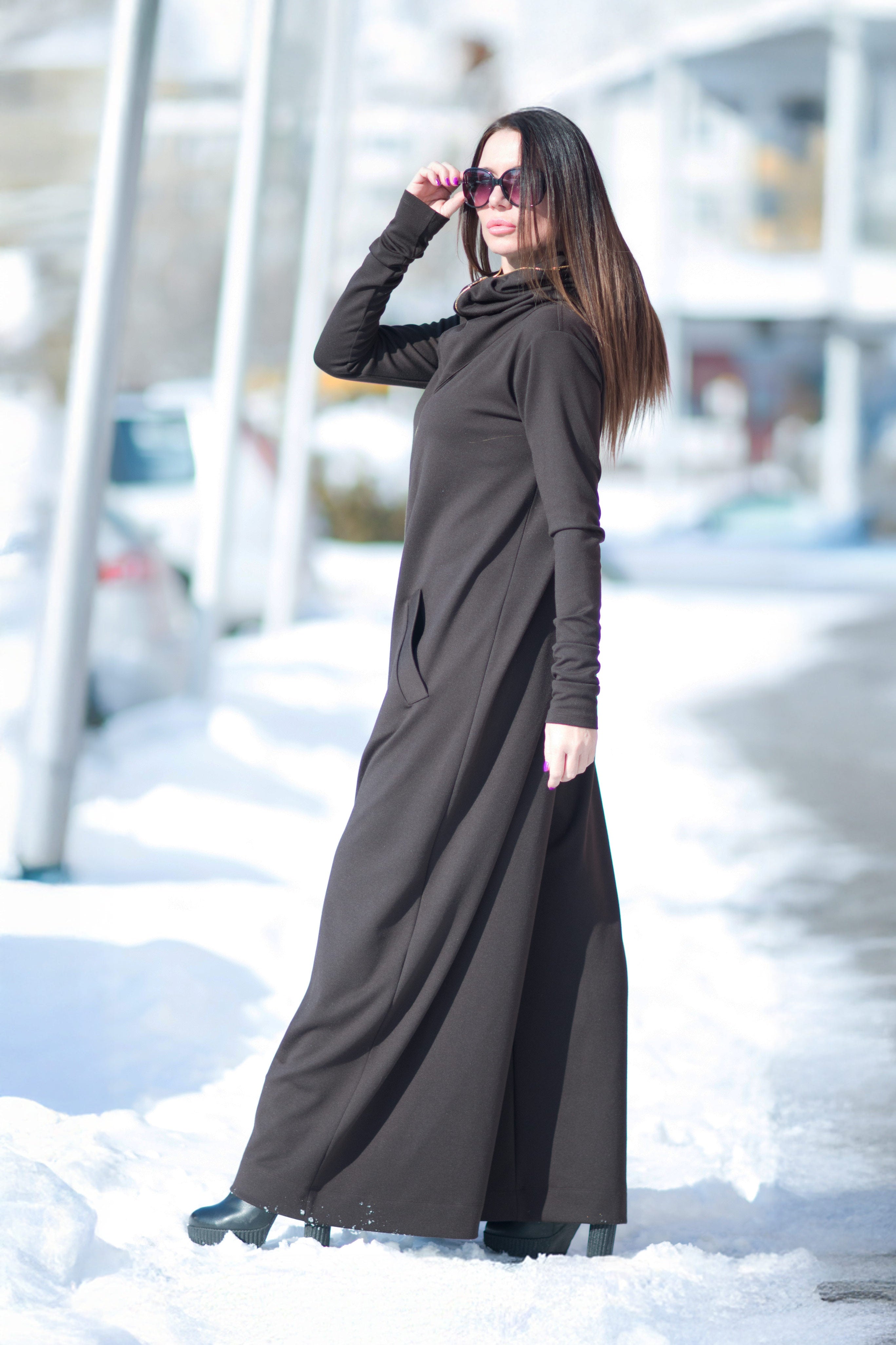 Woman wearing a long black dress standing in a snowy outdoor setting