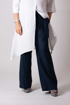Person wearing a white shirt and navy pants on a plain background
