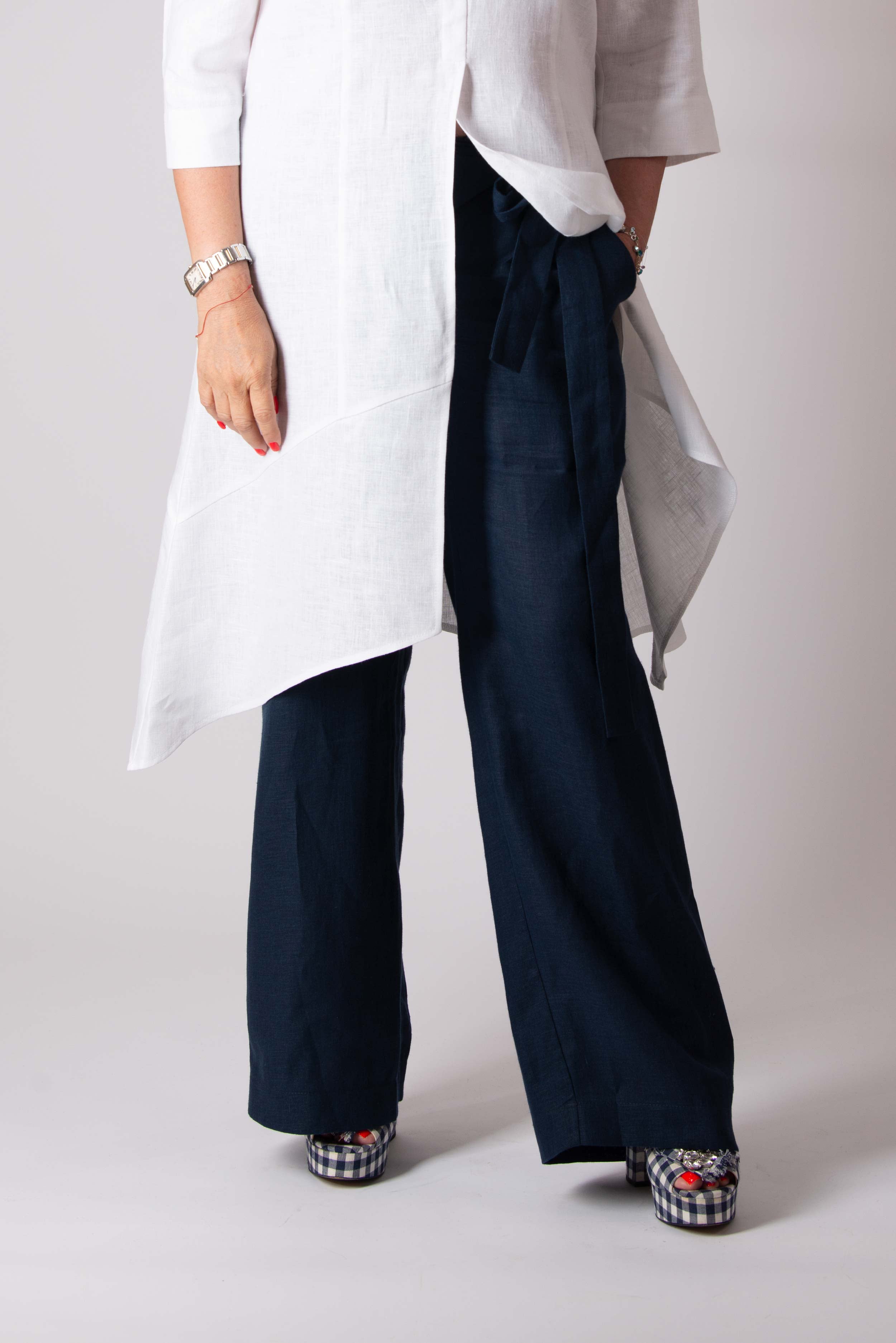 Person wearing a white shirt and navy pants on a plain background