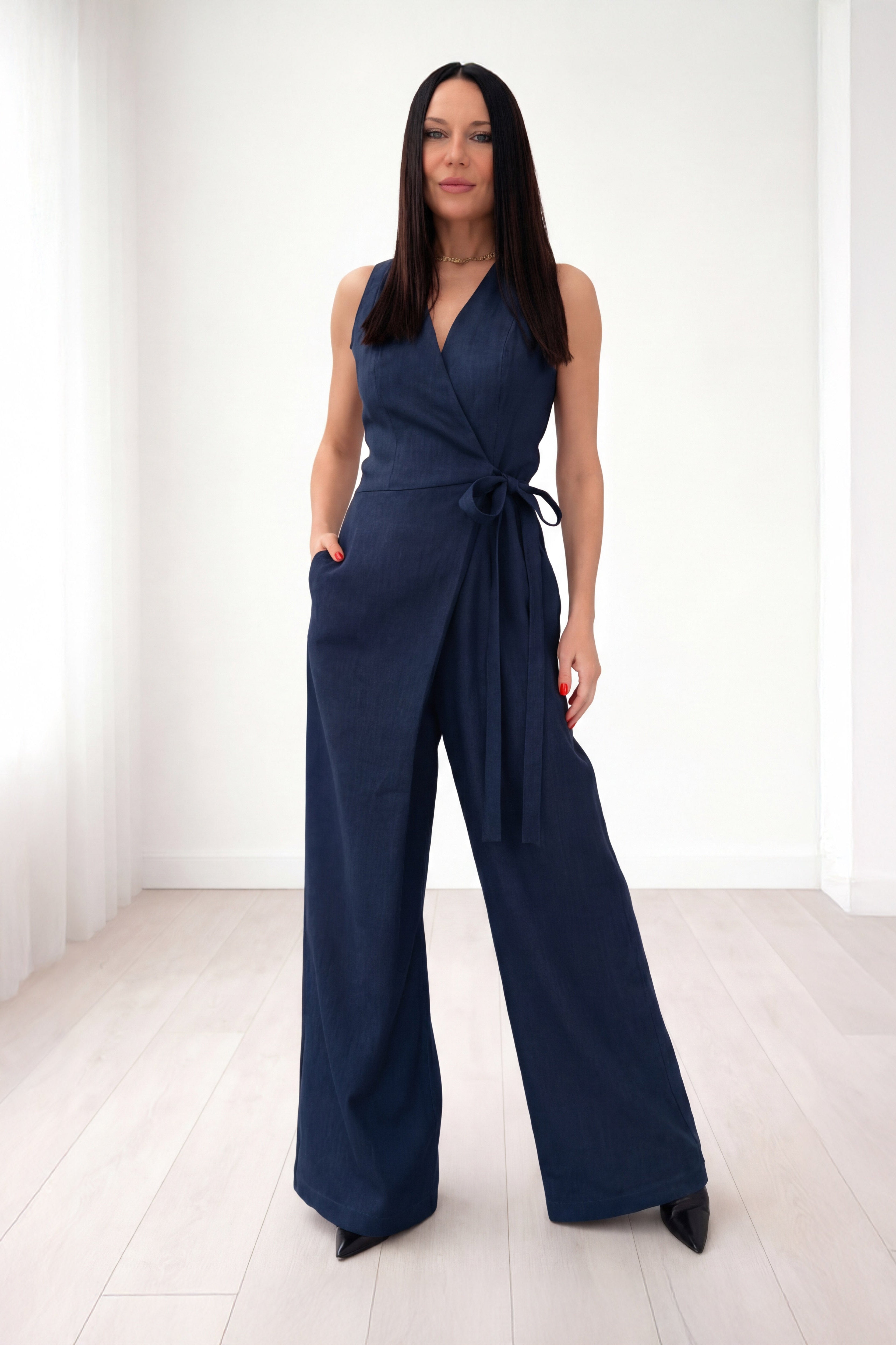 Woman wearing a navy jumpsuit in a white room