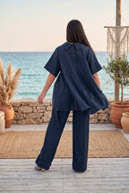 Woman in navy outfit standing on a wooden deck with ocean view