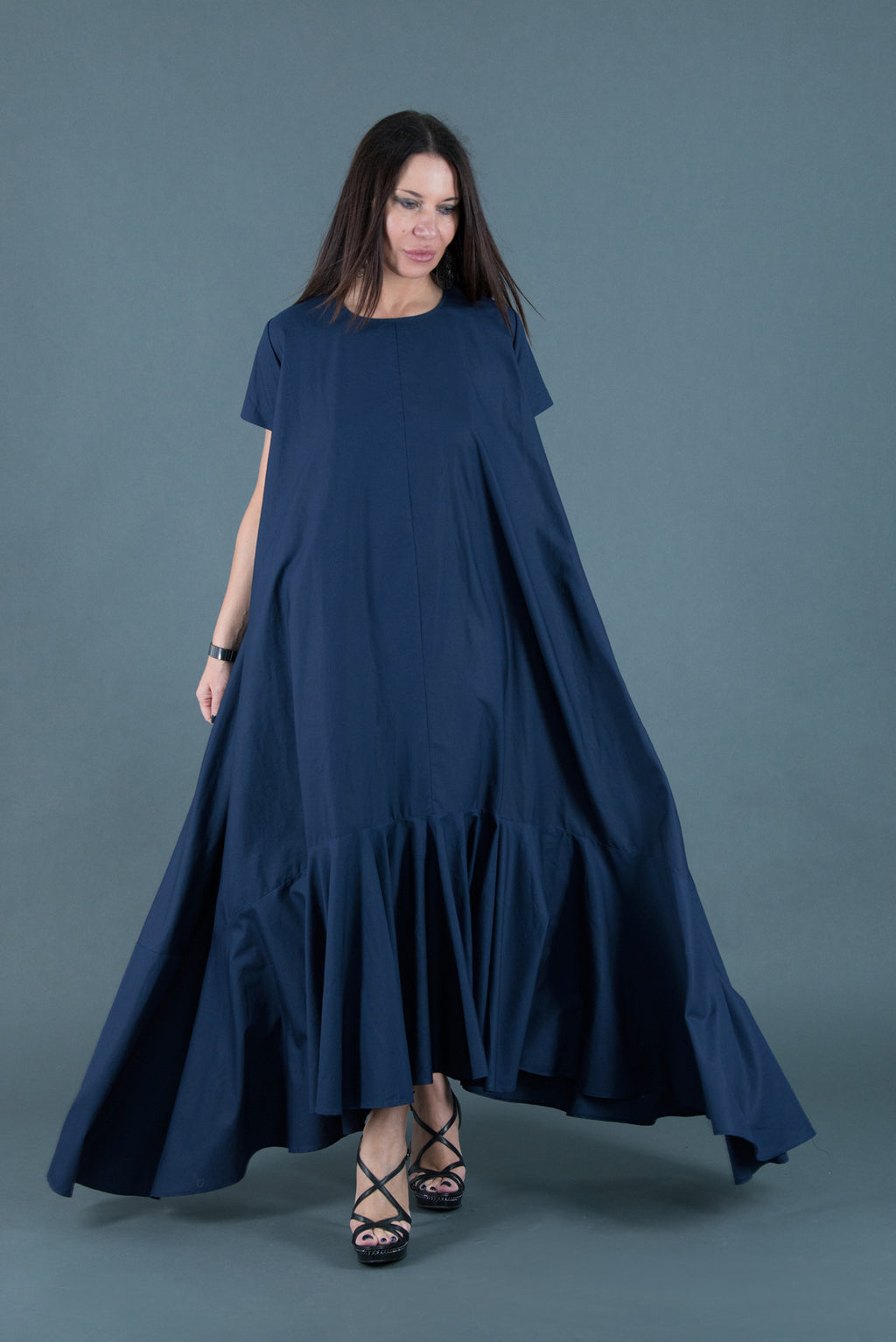 Woman wearing a long navy blue dress against a gray background