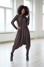 Woman wearing a brown long-sleeve dress in a bright room.