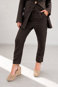 Person wearing a brown suit with beige shoes on a light gray background