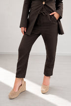 Person wearing a brown suit with beige shoes on a light gray background