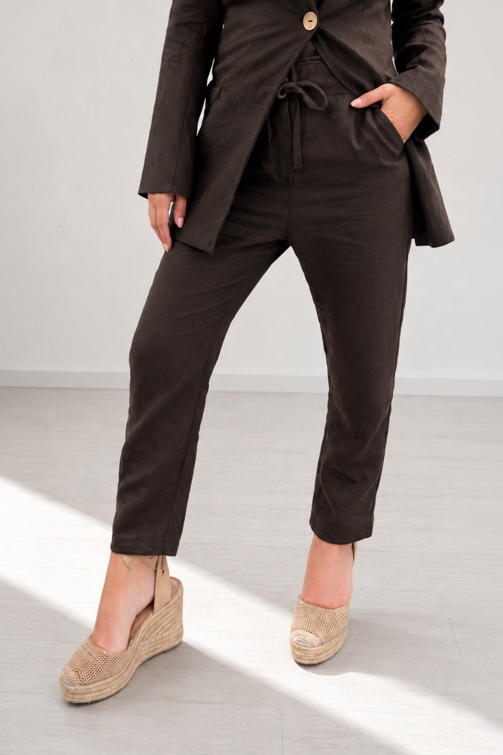 Person wearing a brown suit with beige shoes on a light gray background