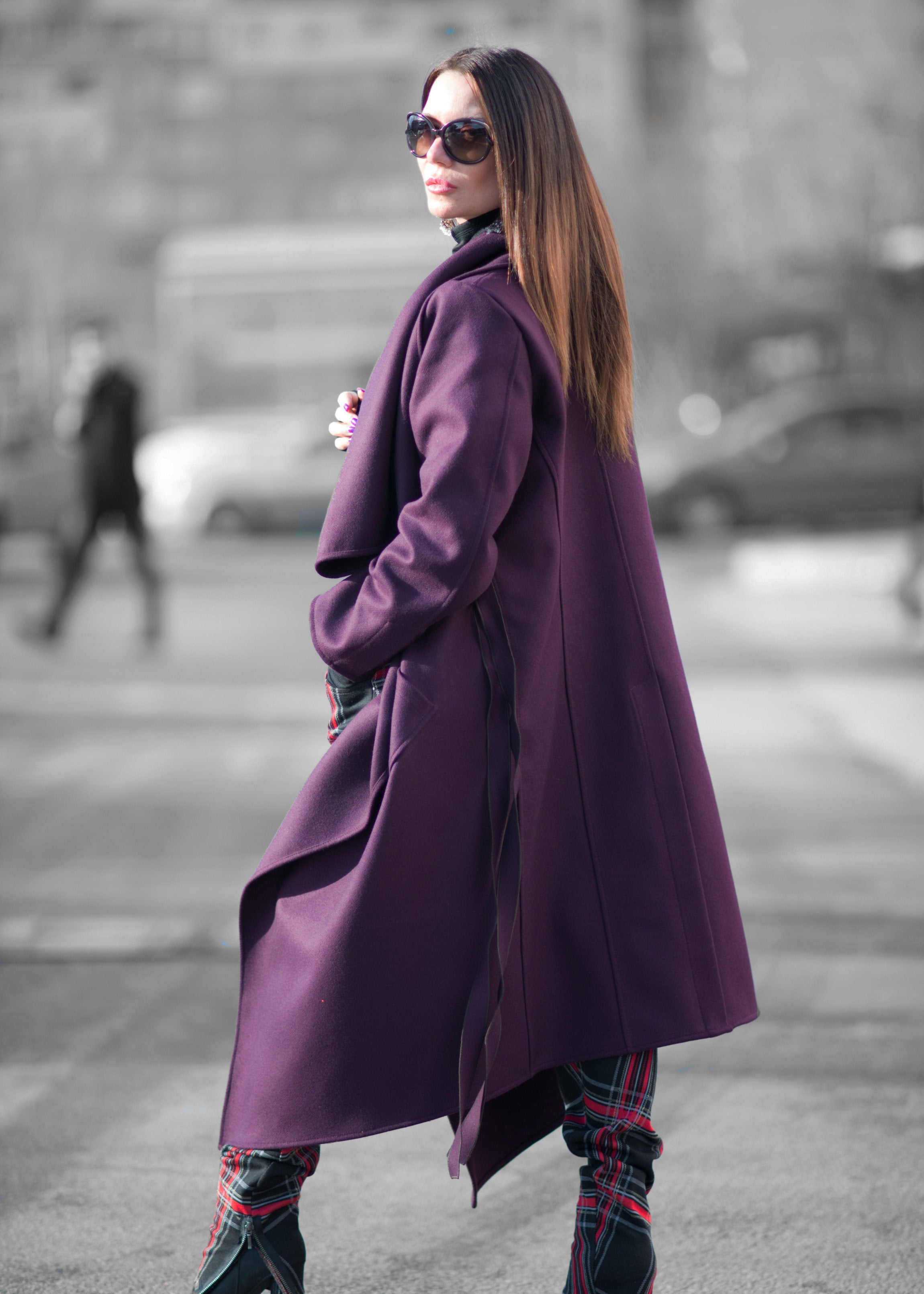 Woman wearing a long purple coat on a city street.