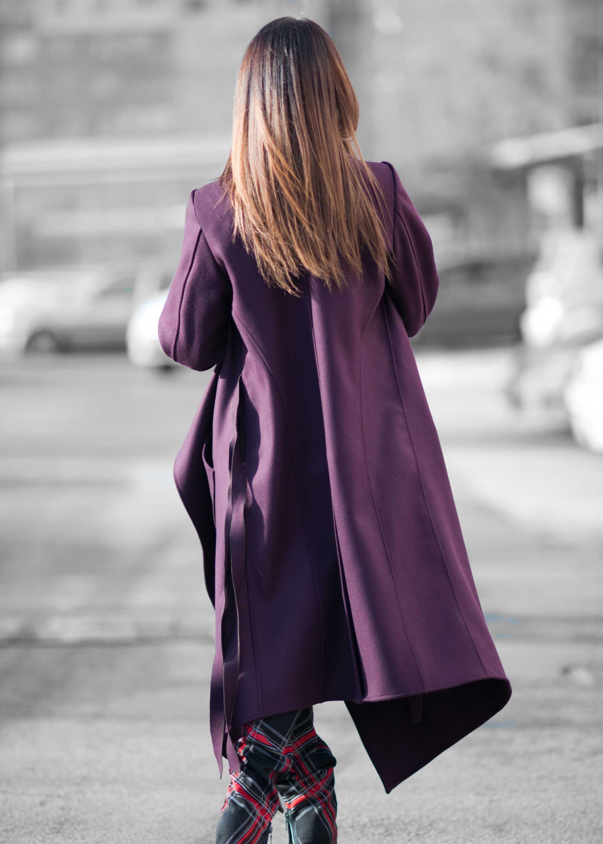 Person wearing a long purple coat walking on a street.