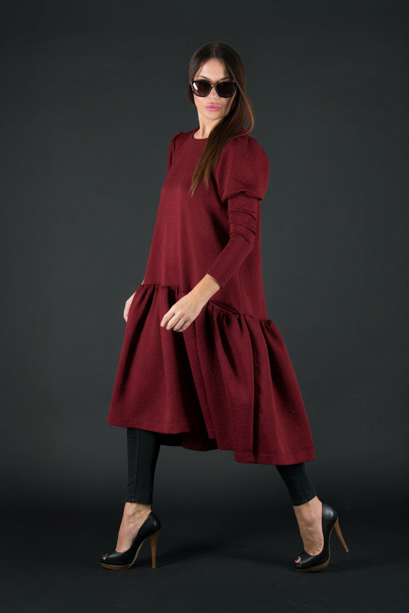 Woman wearing a burgundy dress with a hood on a black background