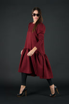 Woman wearing a burgundy dress with a hood on a black background
