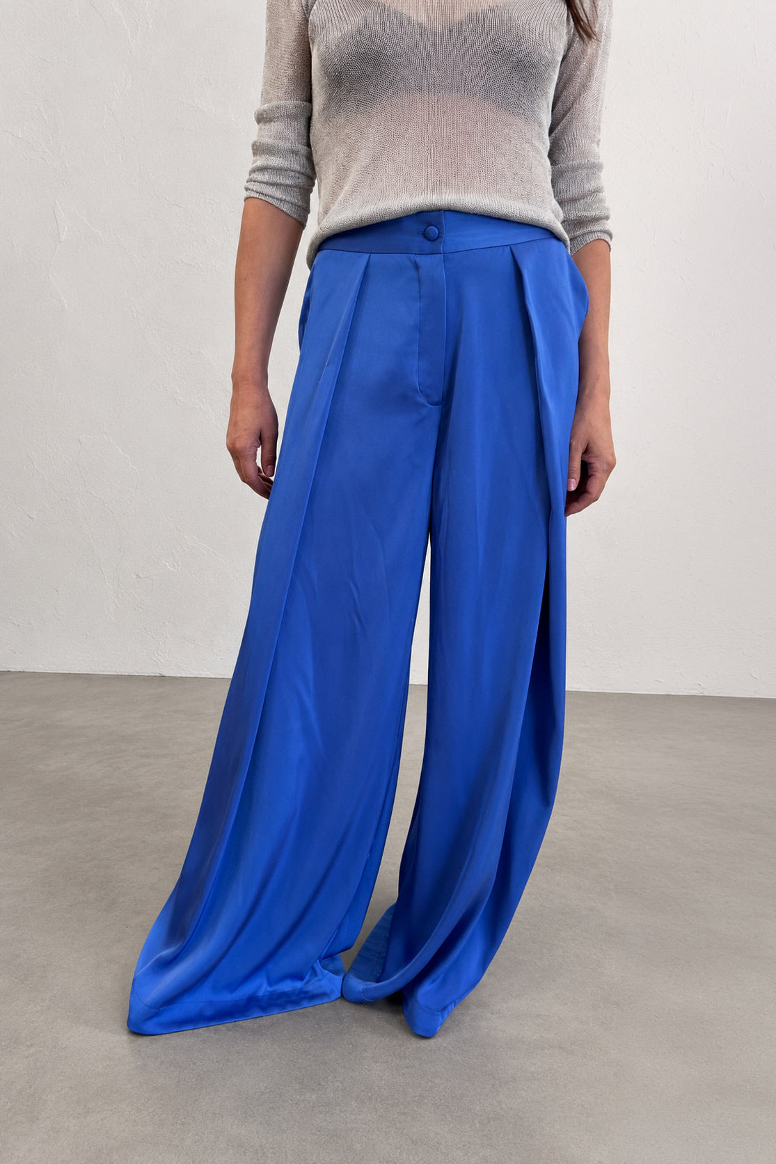 Person wearing blue wide-leg pants and a gray top on a plain background
