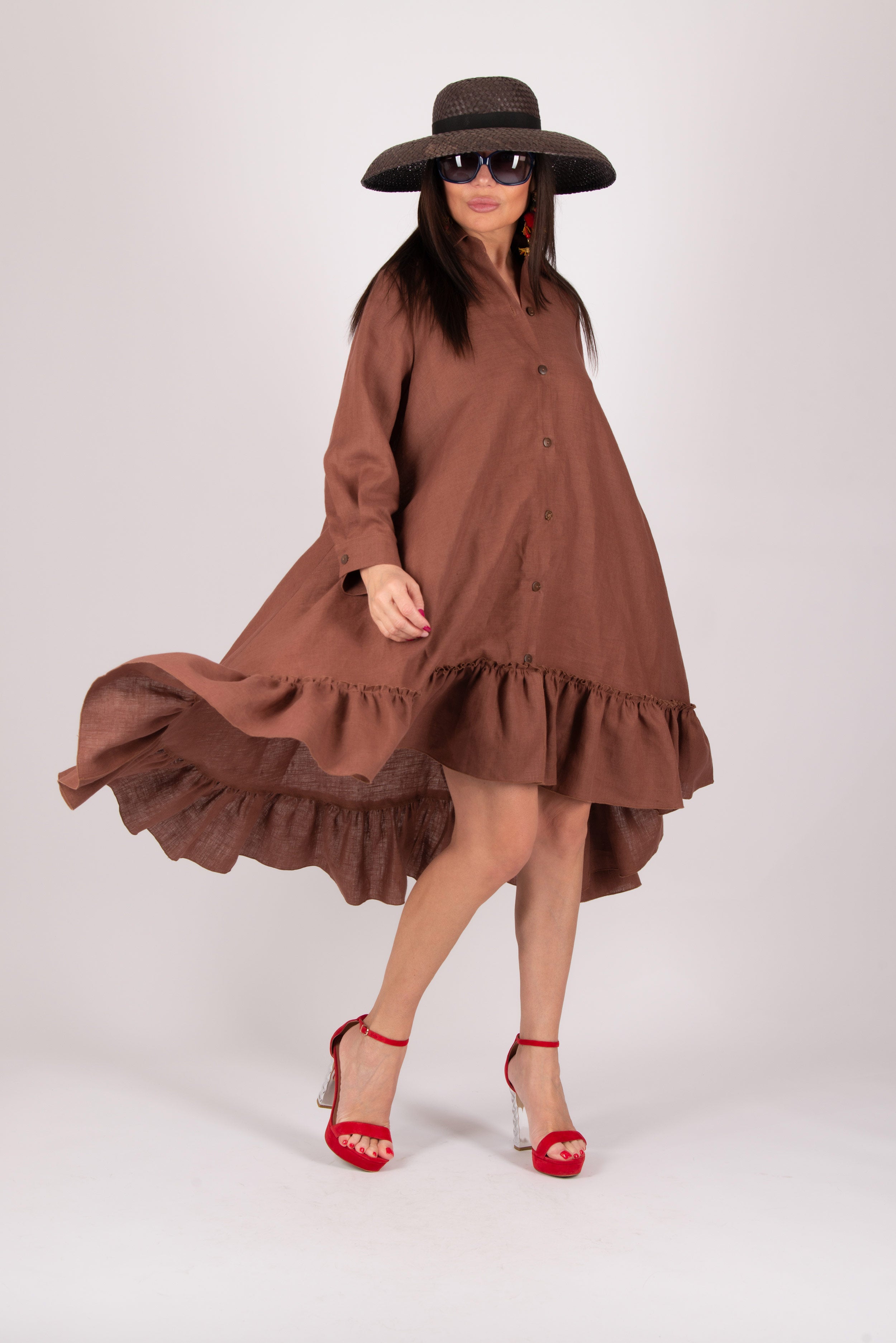 Woman wearing a brown dress with ruffles and a wide-brimmed hat on a white background