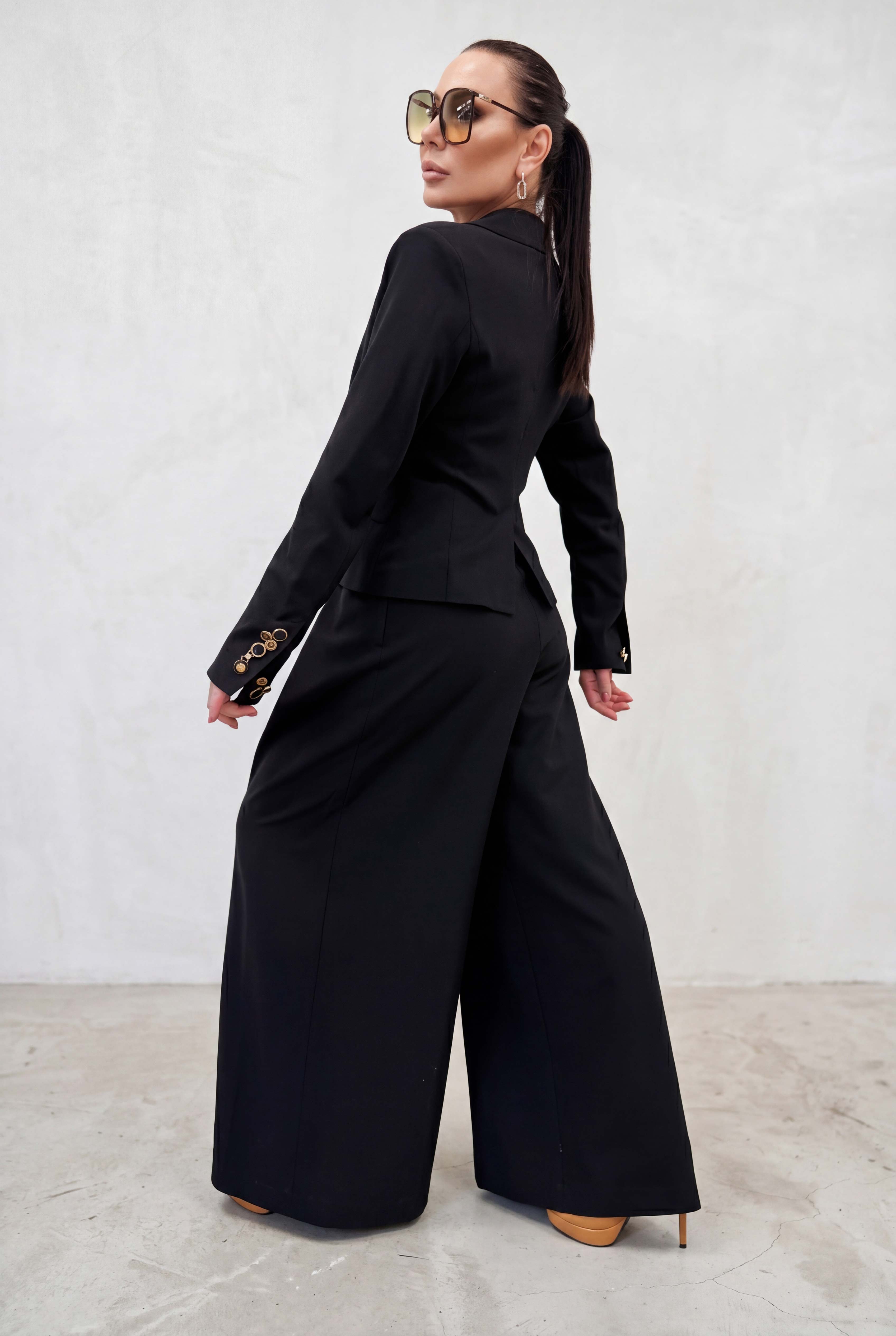 Woman wearing a black outfit with wide-leg pants against a white background