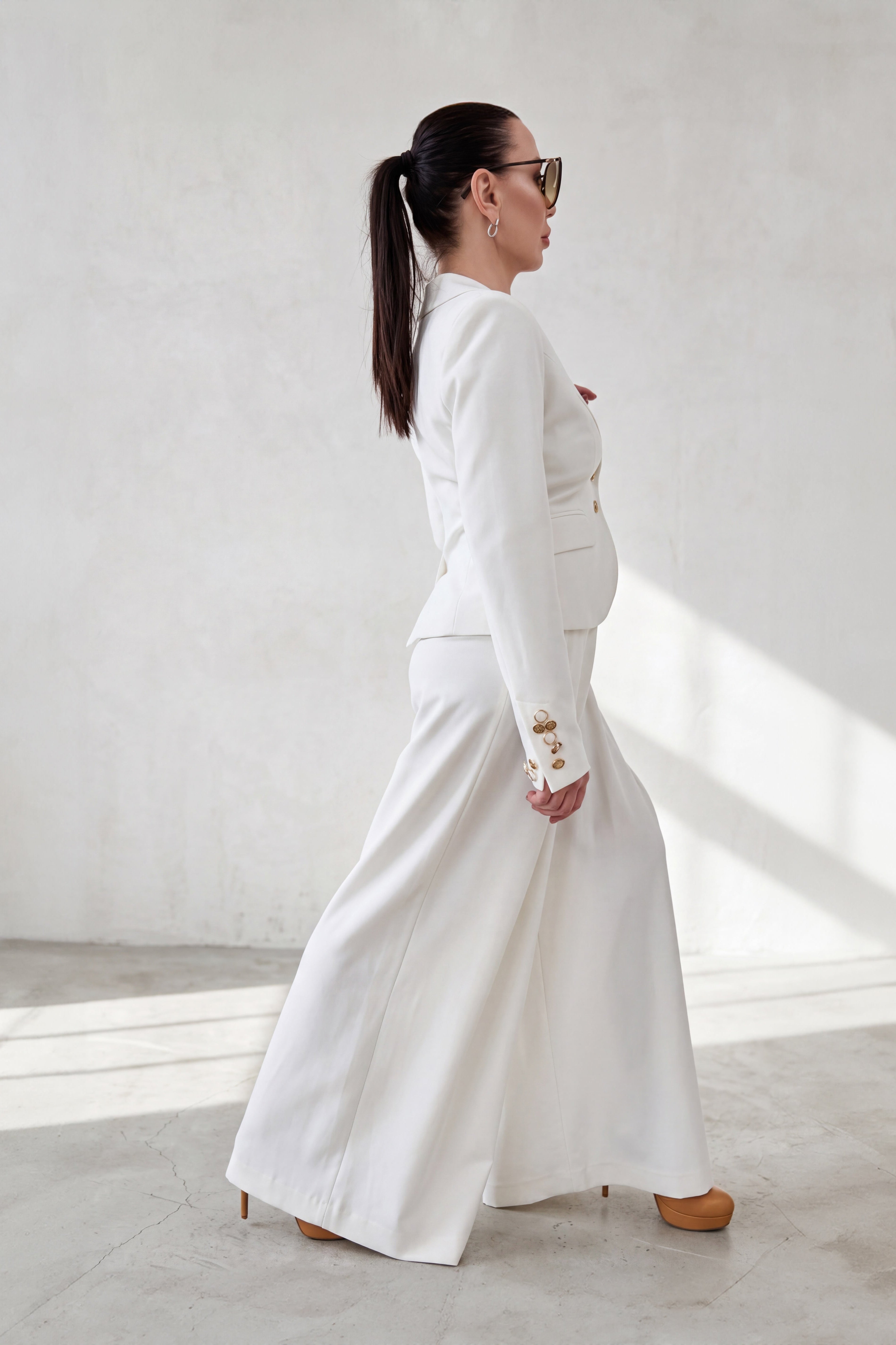 Woman in a white outfit standing against a light background