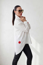 Woman wearing a white shirt with red accents and black pants on a white background