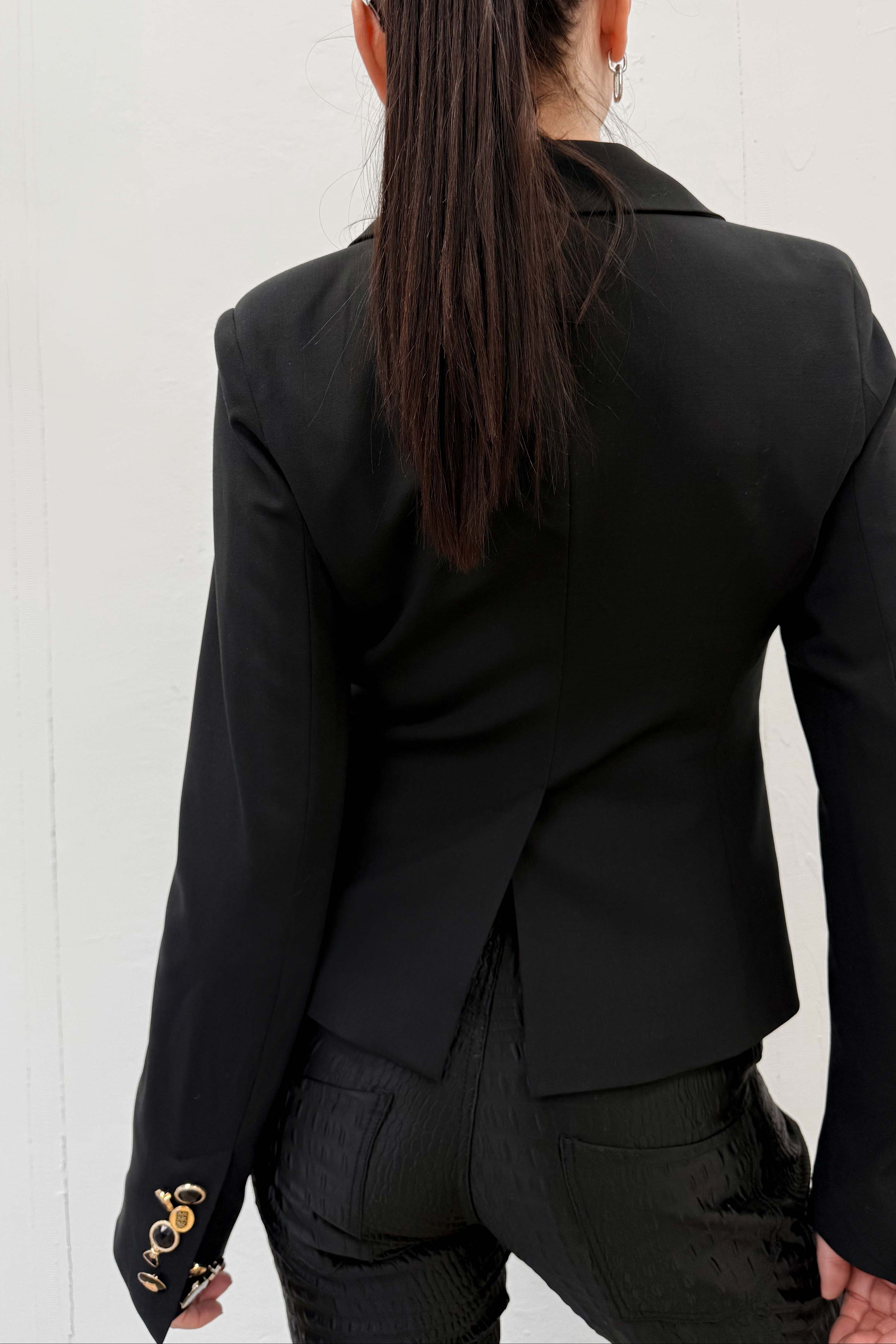 Person wearing a black blazer from behind on a white background