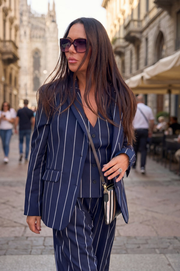 Woman in a blue pinstripe suit walking on a city street.