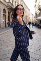 Woman in a navy pinstripe suit walking down a city street.