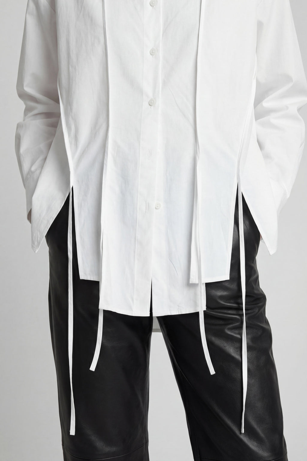 White oversized shirt with black pants on a plain background