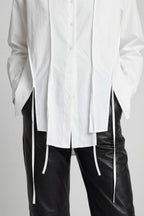 White oversized shirt with black pants on a plain background