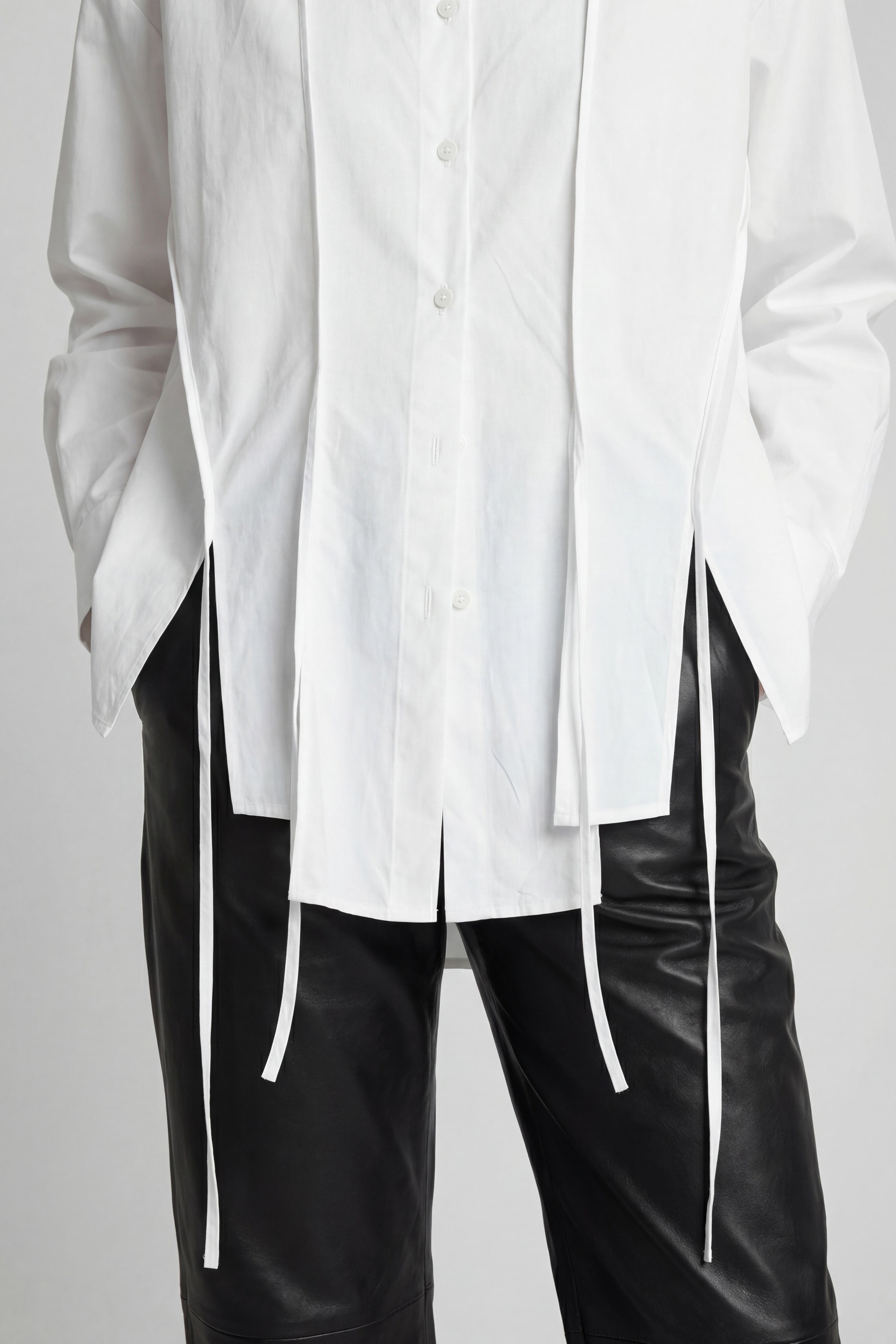 White oversized shirt with black pants on a plain background