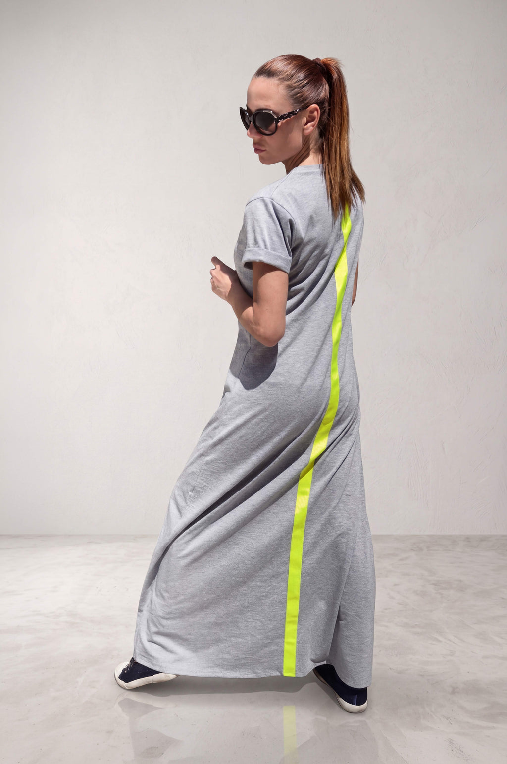 Woman wearing a gray dress with a neon green stripe on the back