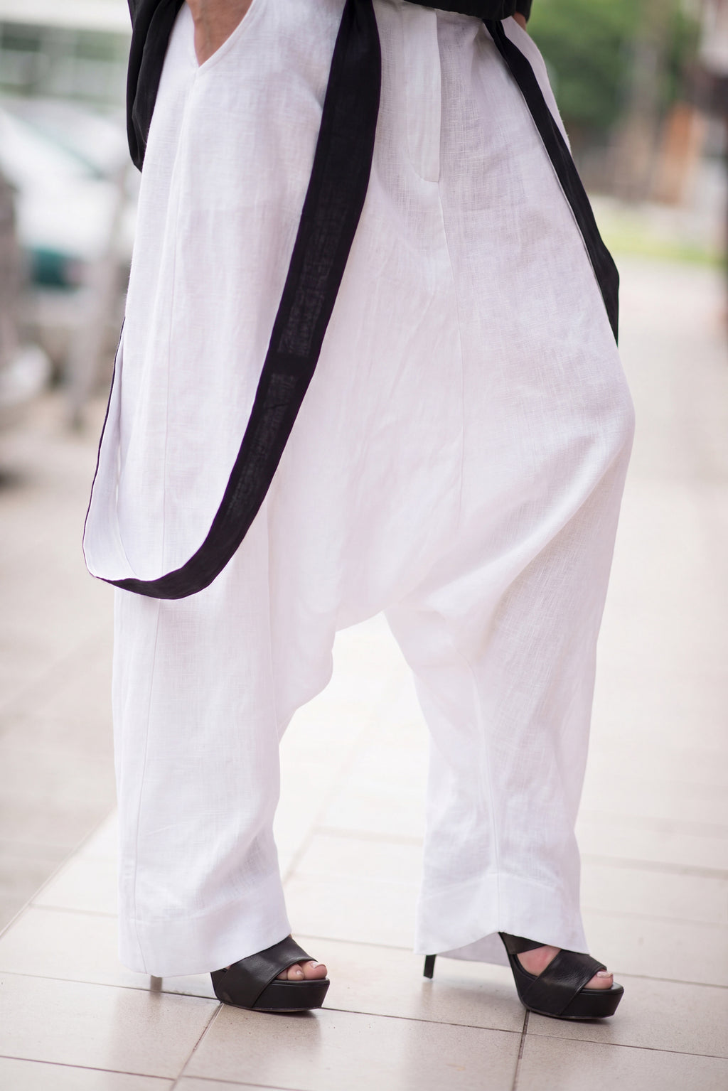 Person wearing white pants with black trim and black shoes on a blurred background