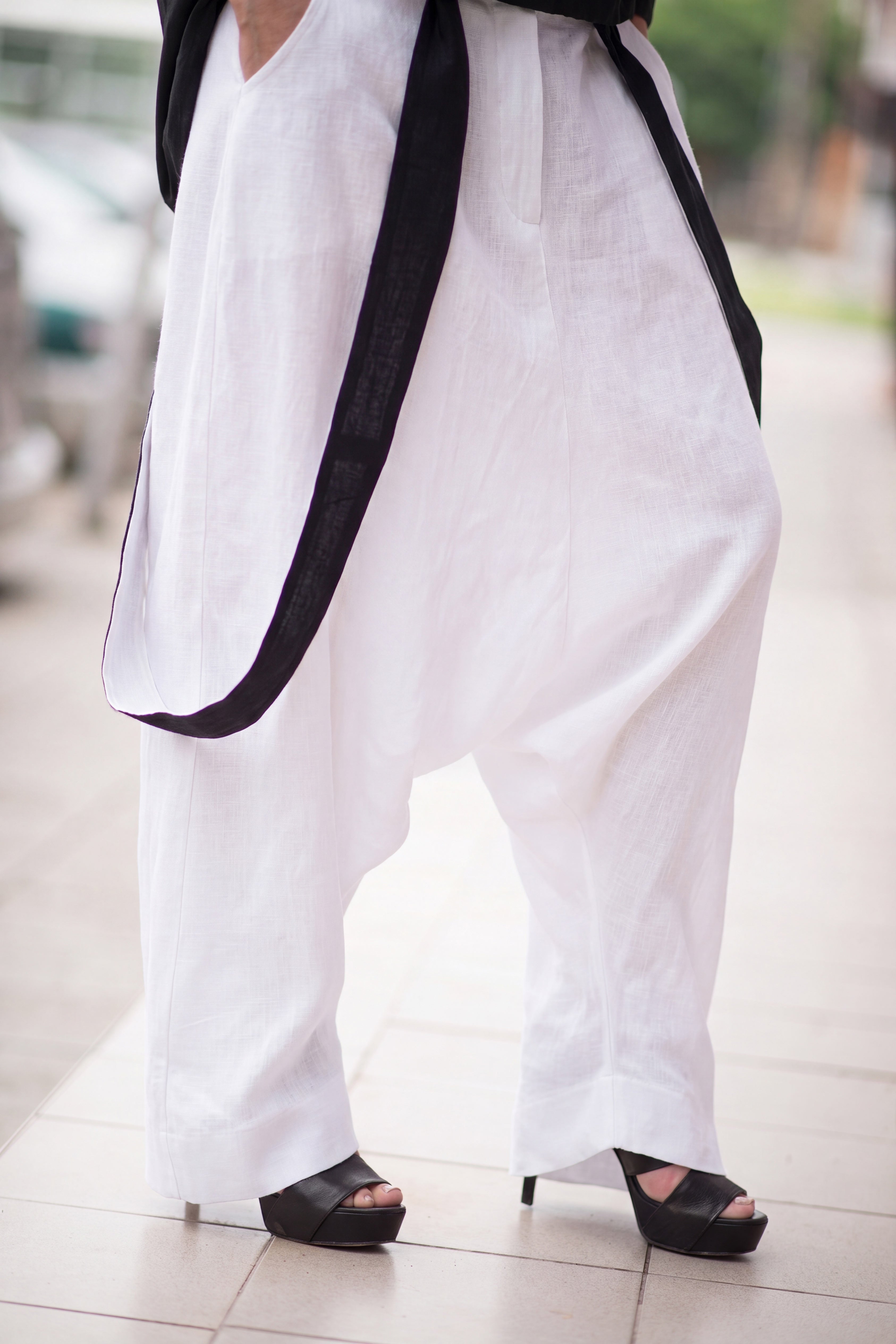 Person wearing white pants with black trim and black shoes on a blurred background
