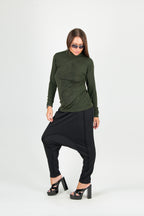 Woman wearing a green top and black harem pants on a white background