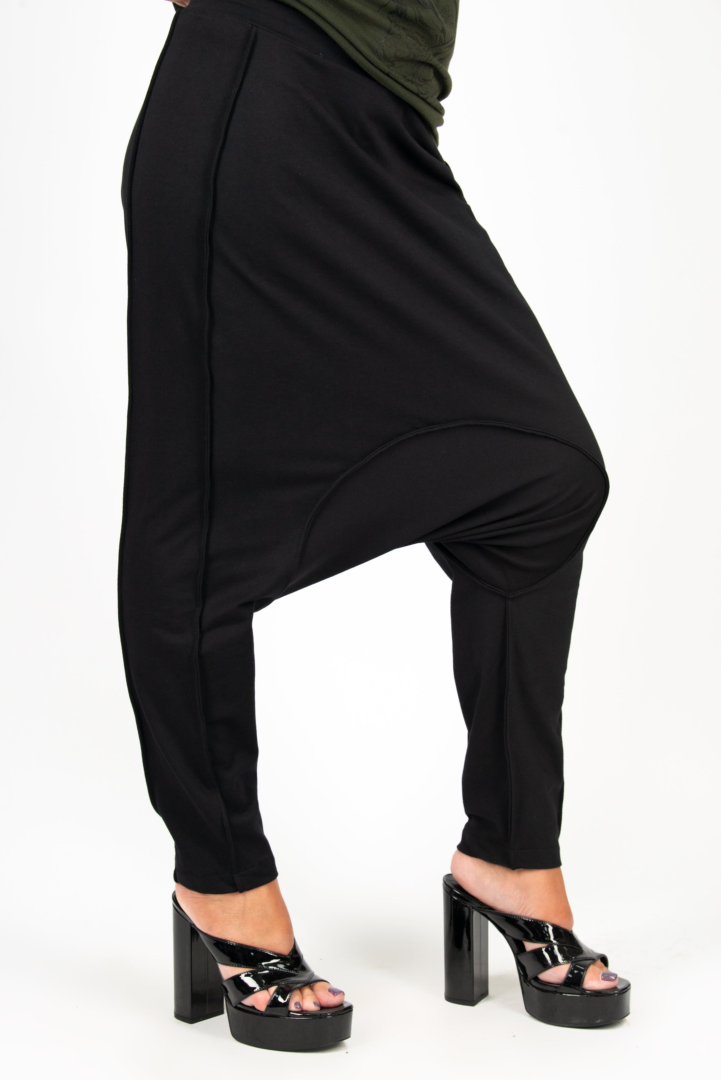 Black harem pants worn by a person on a white background