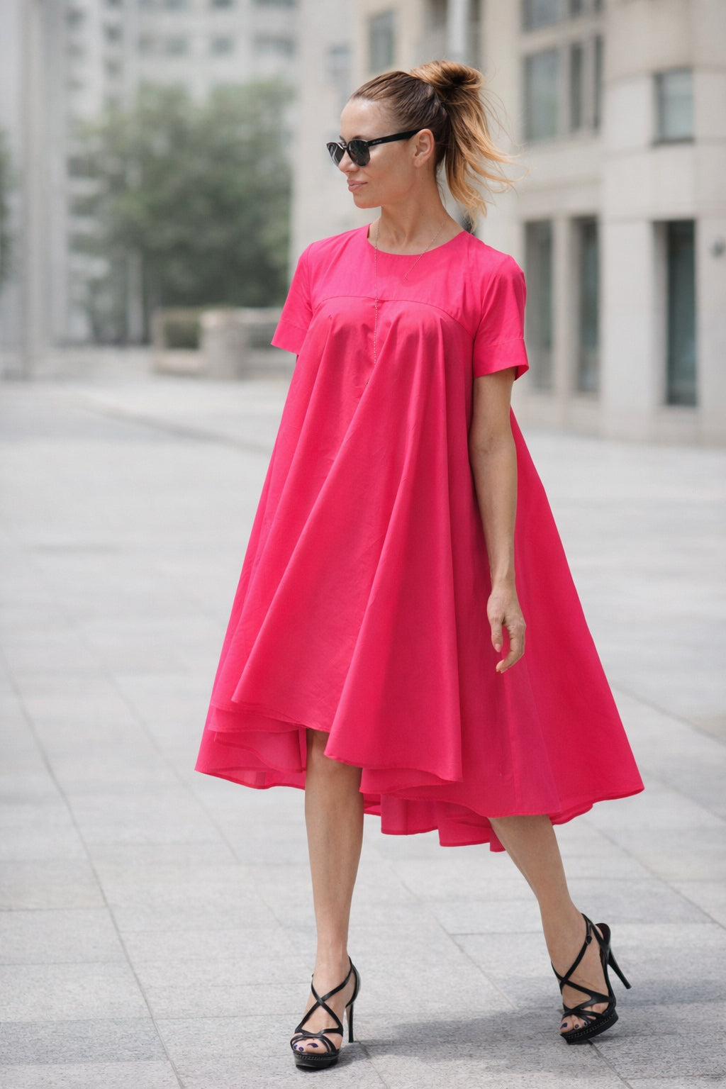Woman wearing a bright pink dress in an urban setting
