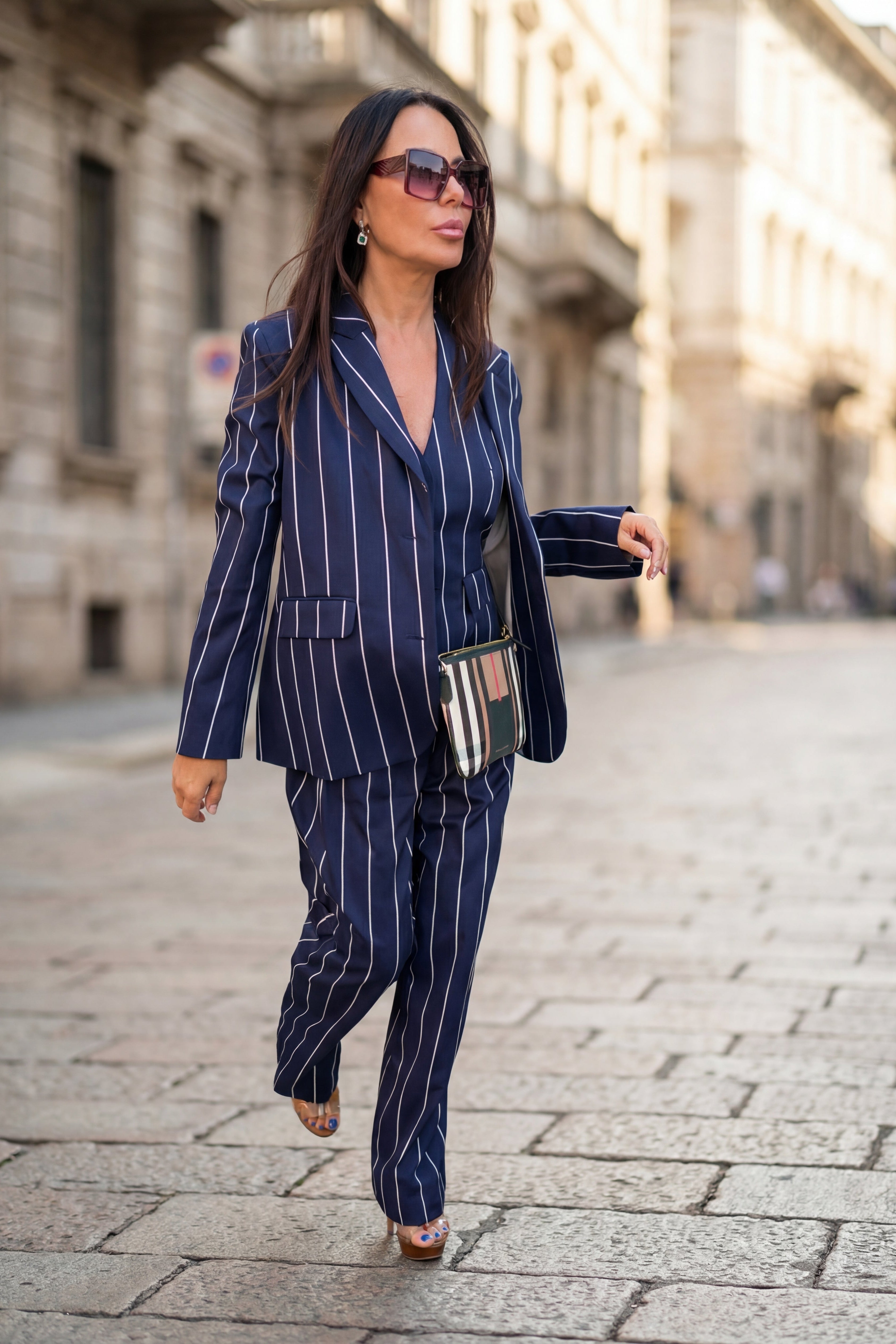 Woman in a pinstripe suit walking on a city street.