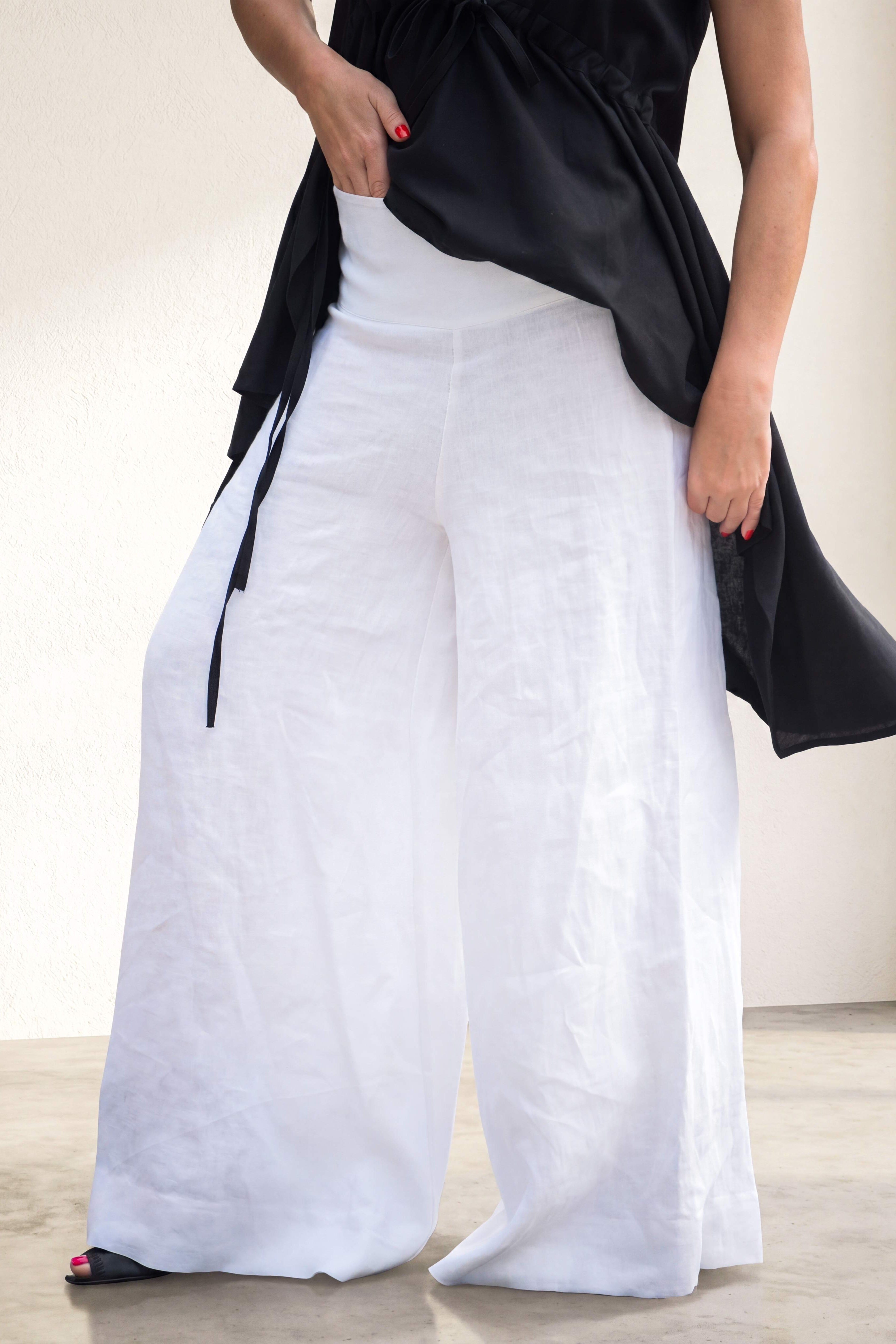 Person wearing a black top and white wide-leg pants on a neutral background