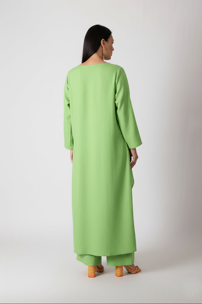 Person wearing a green dress standing against a white background