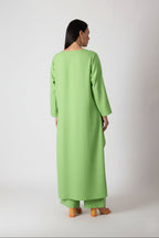 Person wearing a green dress standing against a white background