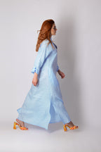 Woman wearing a light blue dress with orange shoes on a white background