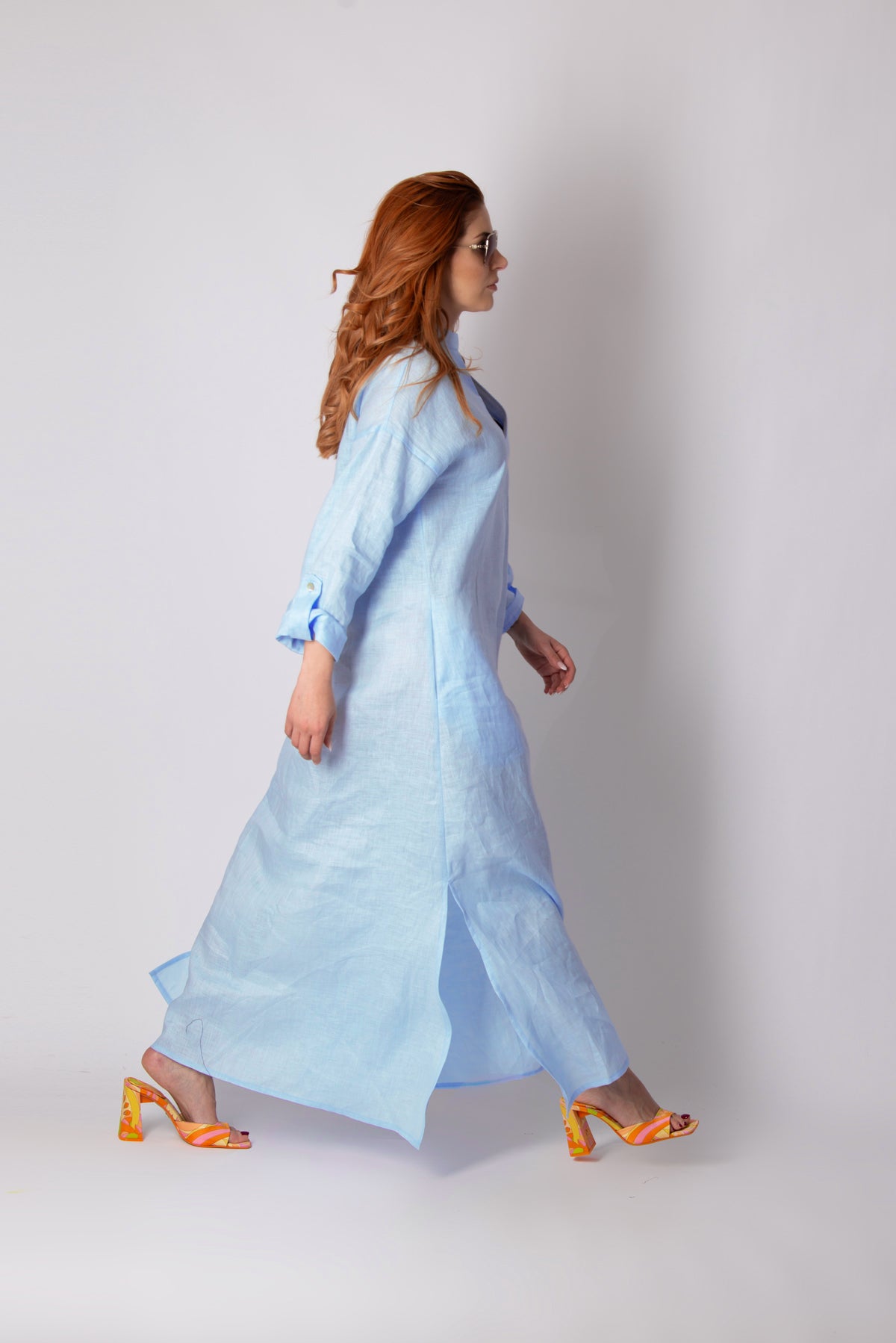 Woman wearing a light blue dress with orange shoes on a white background