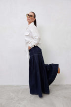 Woman wearing a white blouse and dark blue skirt against a white background