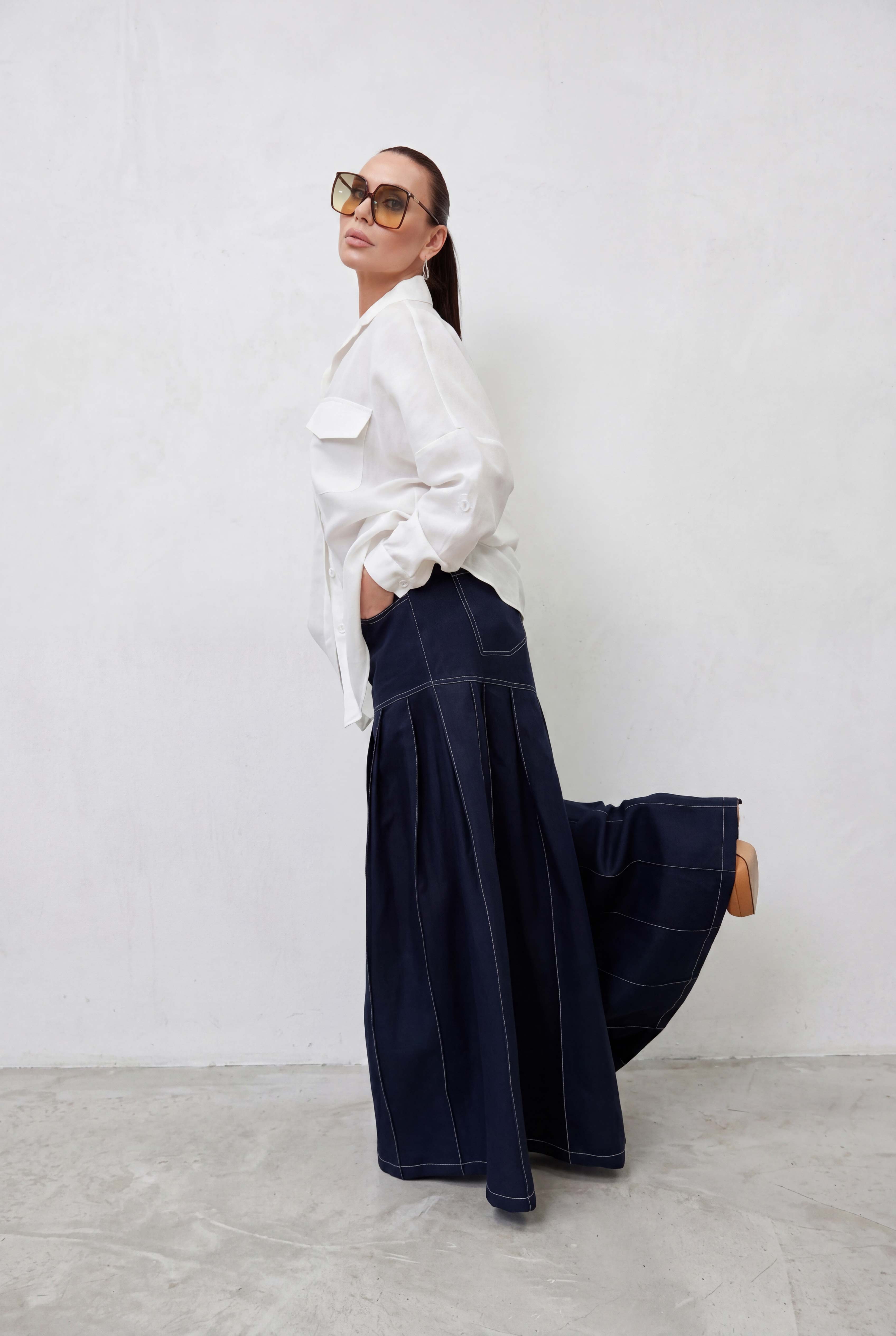 Woman wearing a white blouse and dark blue skirt against a white background
