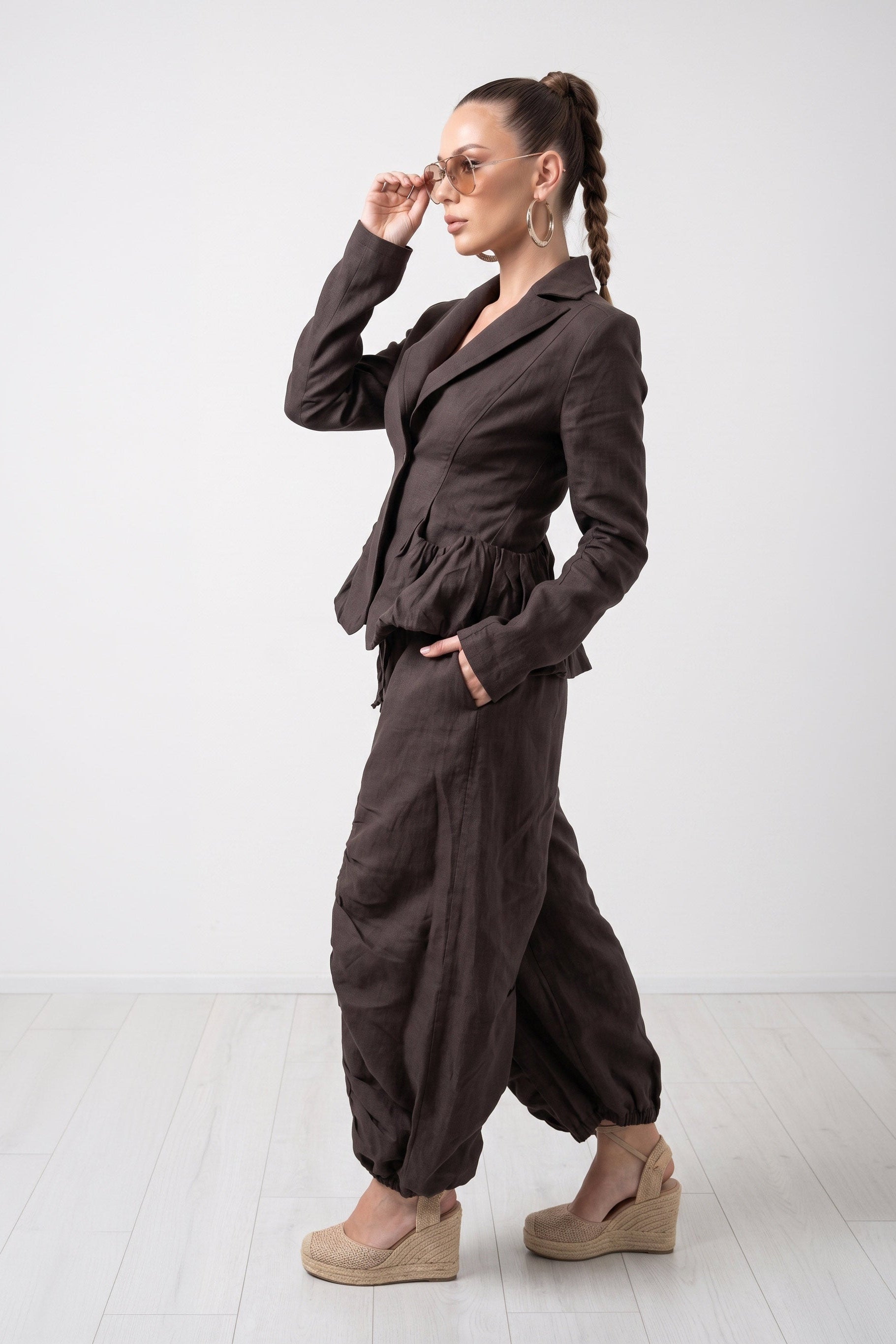 Woman wearing a brown outfit with a jacket and wide-leg pants on a white background