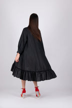 Woman wearing a black dress with a ruffled skirt on a white background