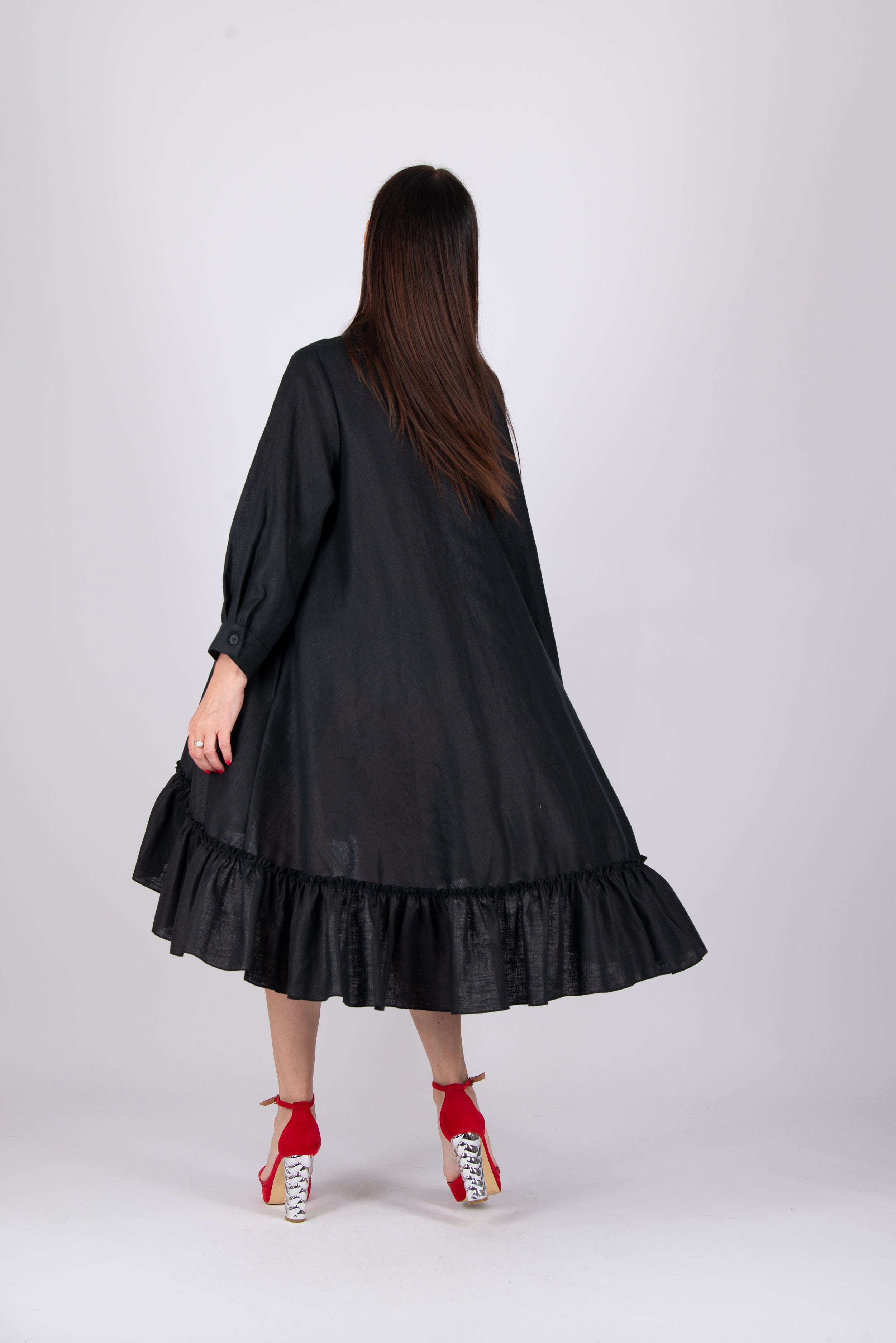 Woman wearing a black dress with a ruffled skirt on a white background