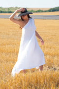 Woman in a white dress and black hat standing in a wheat field