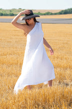 Woman in a white dress and black hat standing in a wheat field
