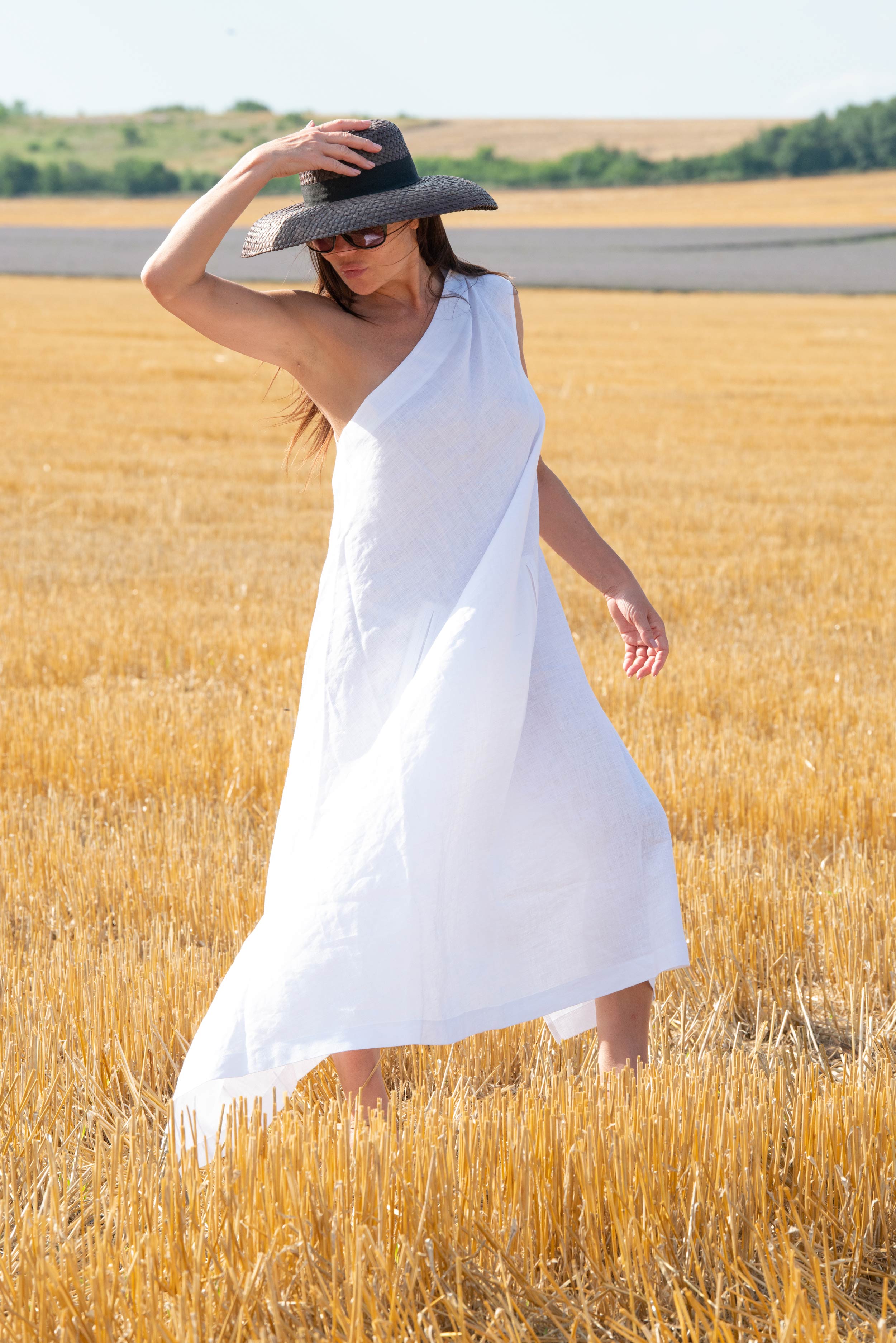 Woman in a white dress and black hat standing in a wheat field